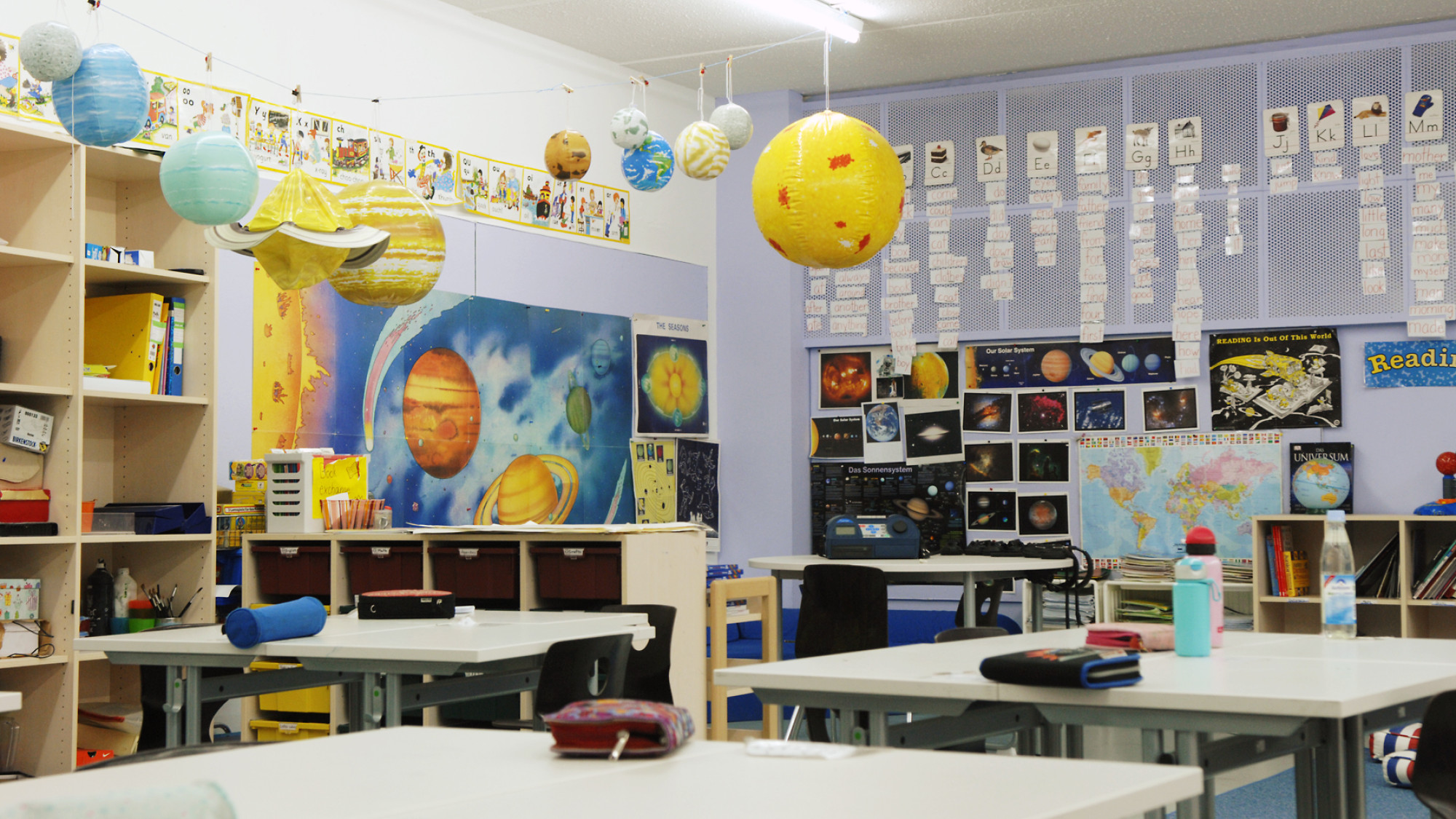 Leeres Klassenzimmer mit Poster und Modellen von Planeten.